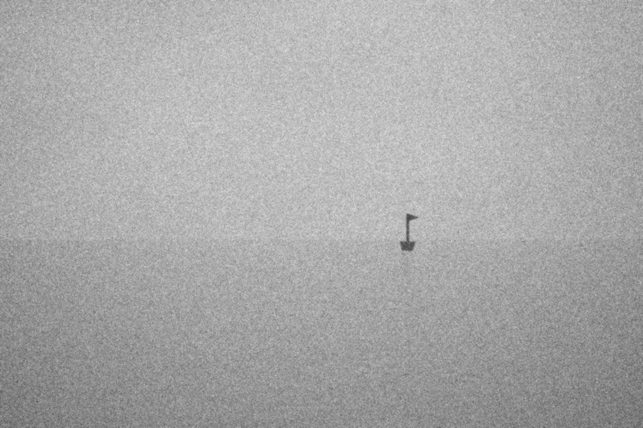 A marker post standing in fog over flat water