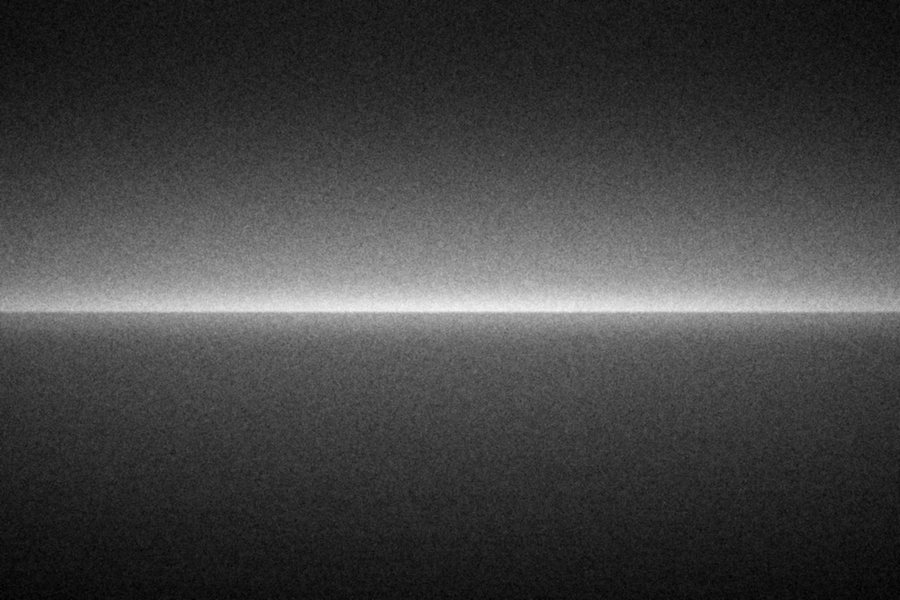 A smooth dark sea and a sky brightening towards a sharp horizon