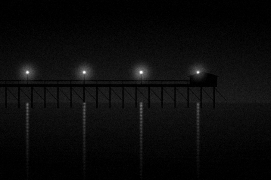 A pier at night with four lamps reflected in still water